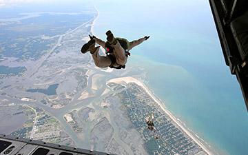 Warfighters with parachutes jumping out the back of a C-17 aircraft 